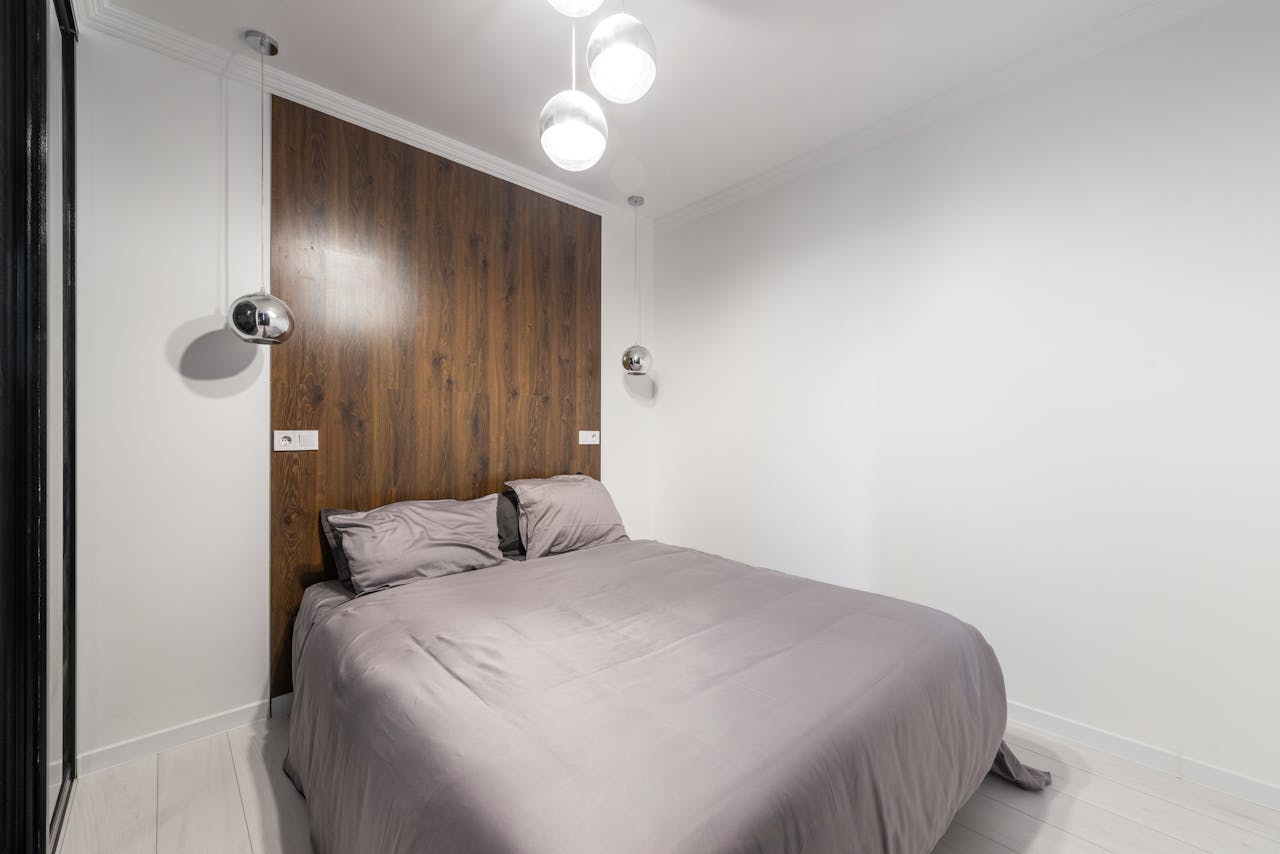 hero-01 Contemporary bedroom with sleek design, wooden accents, and pendant lights.